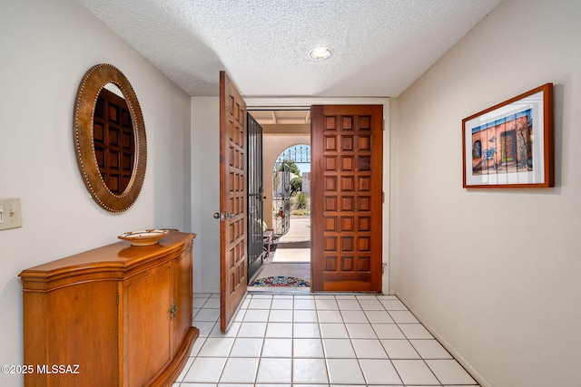 foyer entrance with a textured ceiling and light tile patterned floors