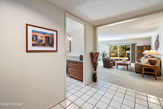 hall with light carpet, light tile patterned flooring, and a textured ceiling