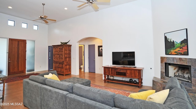 738 S Tohono Ridge Pl, Tucson, AZ 85745 - living room featuring a ceiling fan, a towering ceiling, arched walkways, a tiled fireplace, and recessed lighting