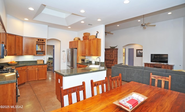 738 S Tohono Ridge Pl, Tucson, AZ 85745 - kitchen with arched walkways, stainless steel appliances, open shelves, light tile patterned floors, and a sink