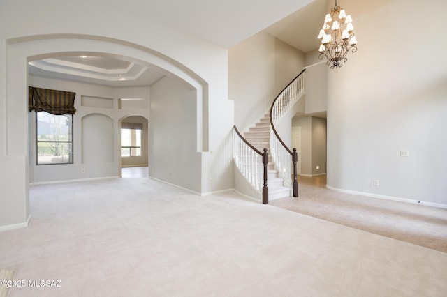 37717 S Terrace Park Dr, Saddlebrooke, AZ 85739 - carpeted foyer entrance featuring arched walkways, a tray ceiling, a chandelier, stairs, and baseboards