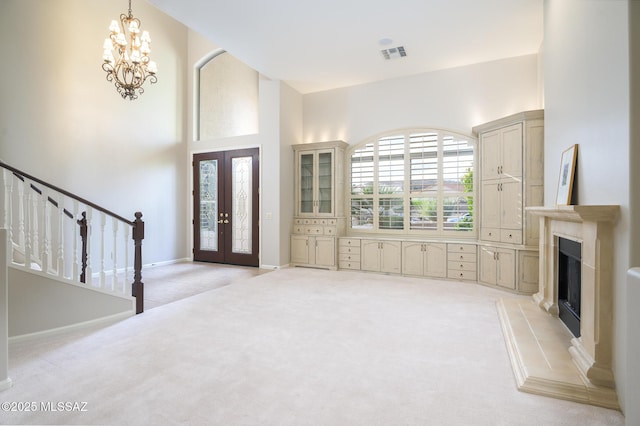 37717 S Terrace Park Dr, Saddlebrooke, AZ 85739 - entrance foyer featuring light carpet, french doors, a chandelier, a fireplace with raised hearth, and stairway