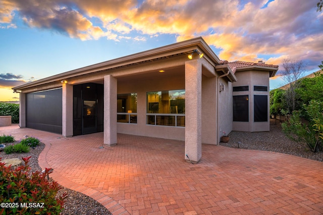 37717 S Terrace Park Dr, Saddlebrooke, AZ 85739 - back of property at dusk featuring stucco siding, a patio area, and a tiled roof