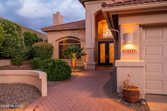 37717 S Terrace Park Dr, Saddlebrooke, AZ 85739 - view of exterior entry with french doors, a tile roof, a chimney, and stucco siding