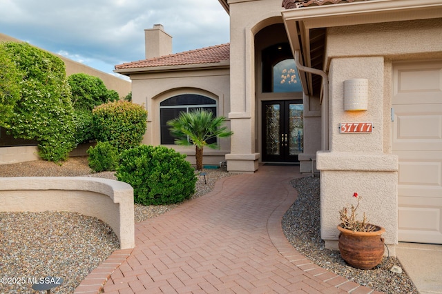 37717 S Terrace Park Dr, Saddlebrooke, AZ 85739 - view of exterior entry featuring french doors, stucco siding, a tiled roof, and a chimney