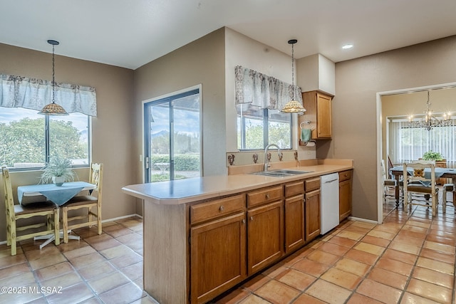 kitchen featuring a sink, light countertops, pendant lighting, and dishwasher