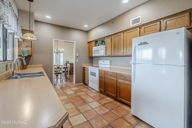 kitchen featuring an inviting chandelier, white appliances, light countertops, visible vents, and a sink
