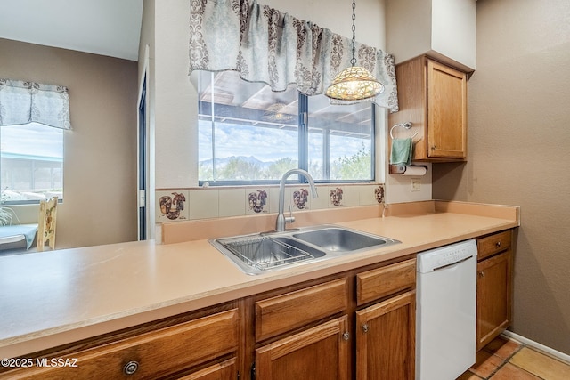 kitchen with light countertops, brown cabinets, dishwasher, and a sink