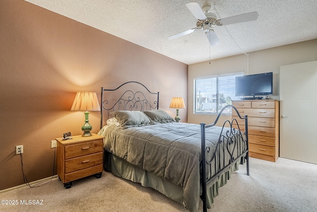 bedroom with ceiling fan, light carpet, and a textured ceiling