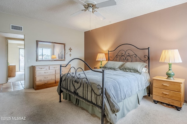 carpeted bedroom with visible vents, a textured ceiling, and ceiling fan