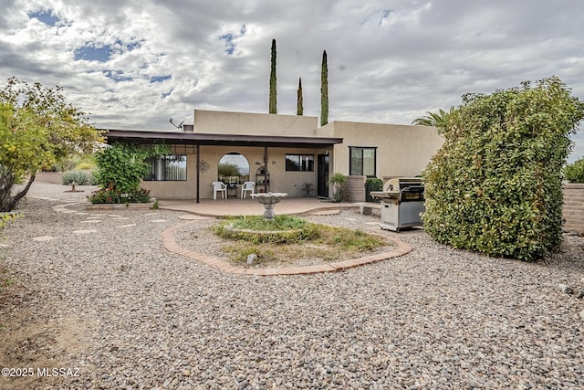 rear view of house featuring a patio area and stucco siding