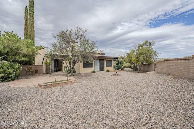 rear view of house with a fenced backyard, a patio, and stucco siding
