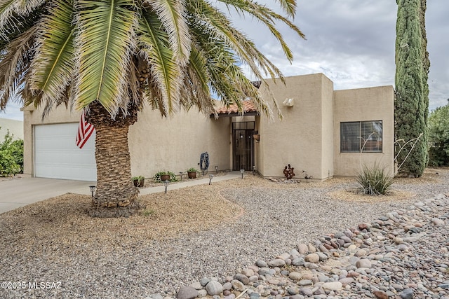 view of front of home featuring concrete driveway, stucco siding, and a garage
