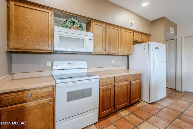 kitchen featuring white appliances, visible vents, light countertops, and brown cabinets