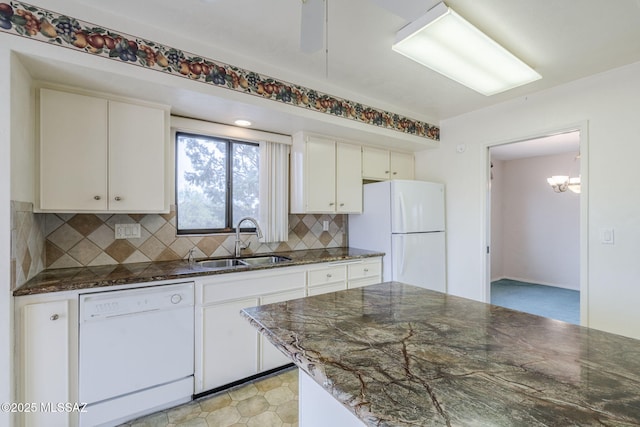 kitchen with dark stone countertops, white appliances, decorative backsplash, white cabinets, and a sink