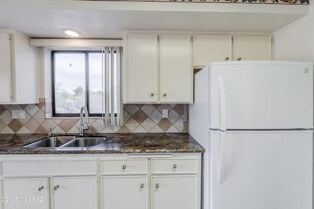 kitchen with white cabinetry, decorative backsplash, freestanding refrigerator, and a sink