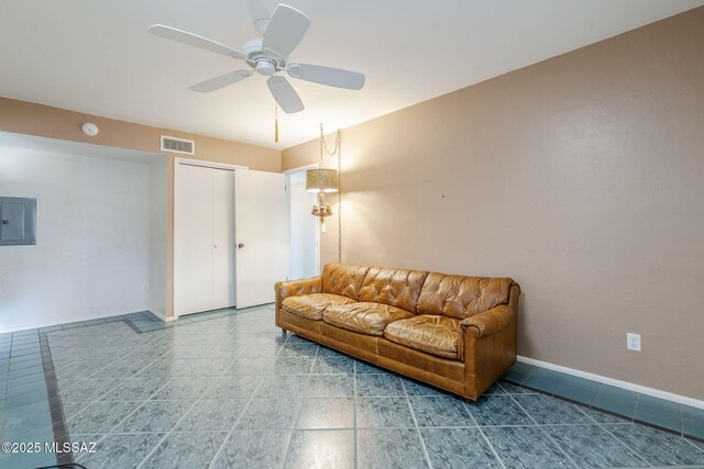 tiled living room featuring visible vents, ceiling fan, electric panel, and baseboards
