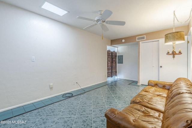 living area featuring baseboards, visible vents, ceiling fan, and electric panel
