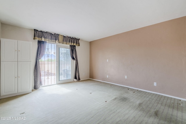 spare room featuring baseboards and light colored carpet