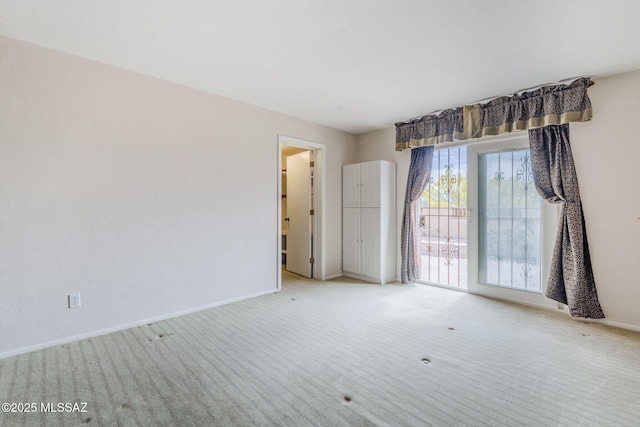 spare room featuring baseboards and light colored carpet