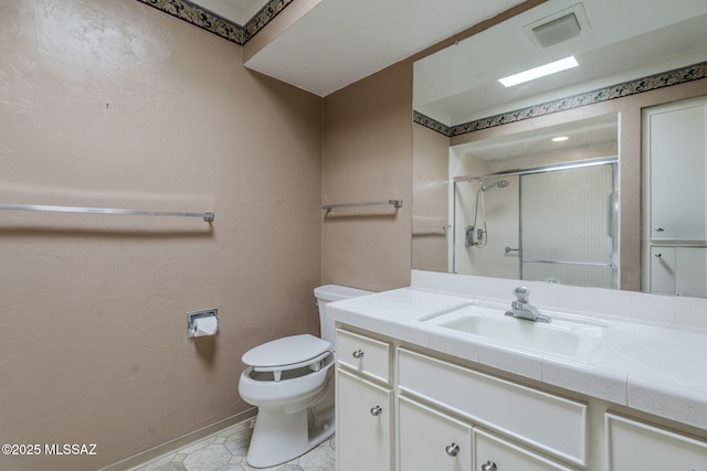 bathroom with toilet, vanity, baseboards, visible vents, and a stall shower