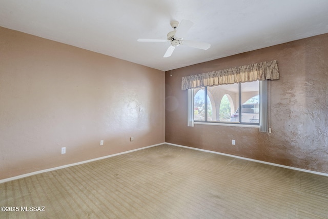 empty room featuring a ceiling fan, carpet floors, and baseboards
