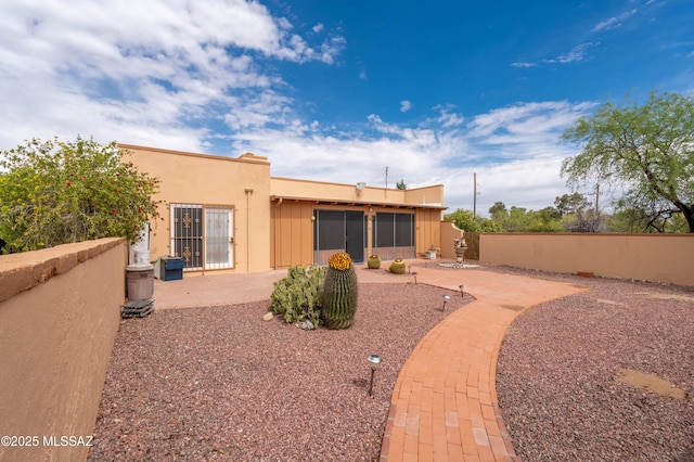 rear view of property with fence, stucco siding, and a patio area