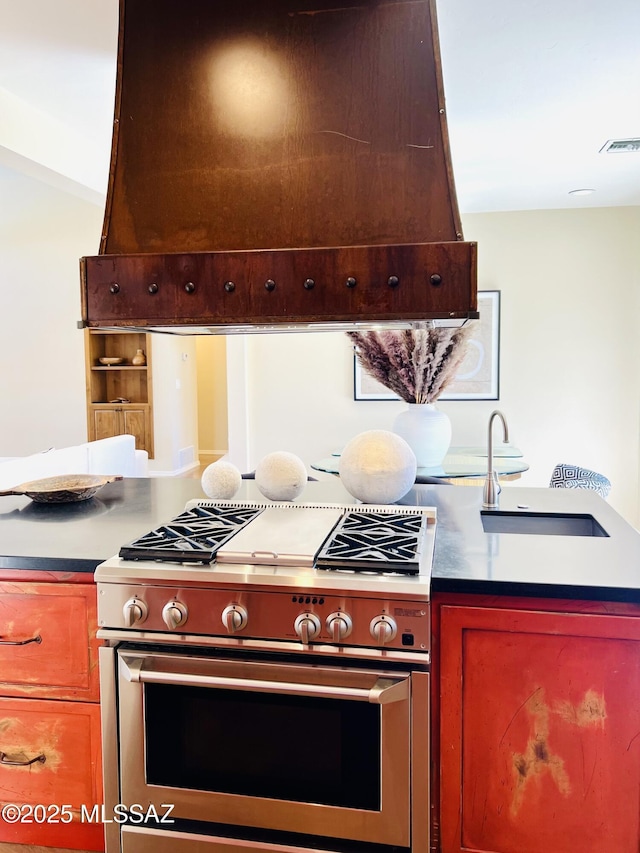kitchen with custom exhaust hood, visible vents, a sink, and stainless steel range