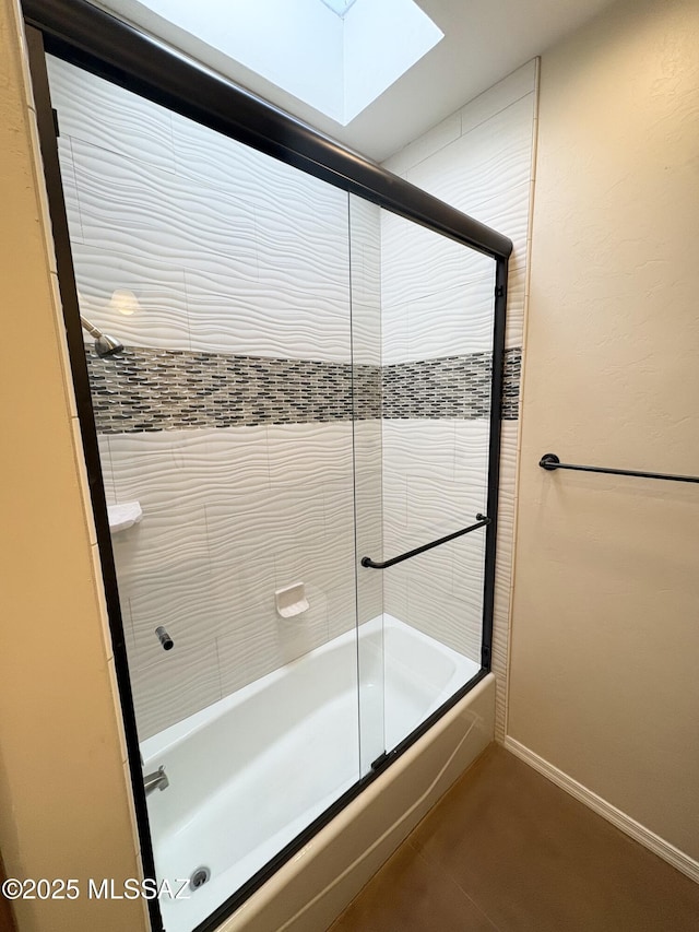 full bathroom with shower / bath combination with glass door, a skylight, and baseboards