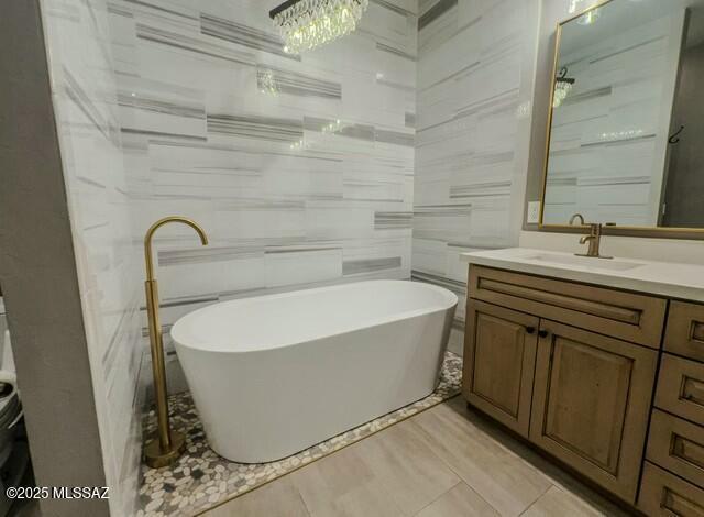 bathroom with a freestanding bath, tile walls, and vanity