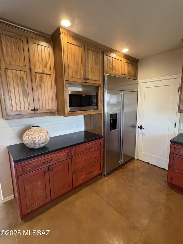 kitchen featuring brown cabinets, dark countertops, stainless steel appliances, and recessed lighting