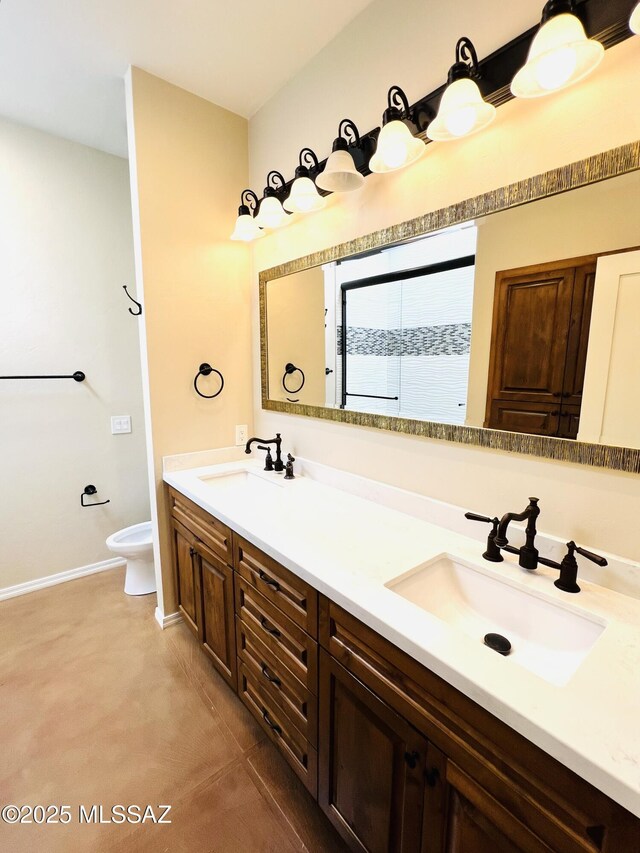 bathroom featuring baseboards, toilet, a sink, and double vanity