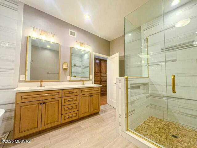 bathroom featuring double vanity, visible vents, a stall shower, and a sink