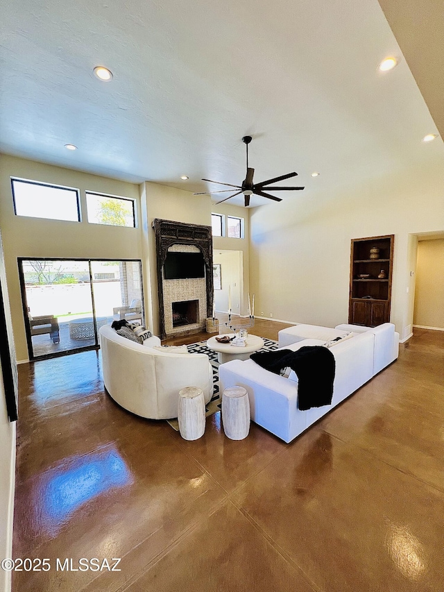 living room featuring a ceiling fan, finished concrete floors, a stone fireplace, and recessed lighting