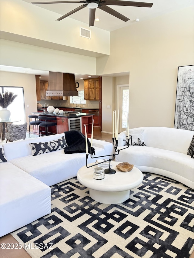 living room with a towering ceiling, visible vents, ceiling fan, and a healthy amount of sunlight