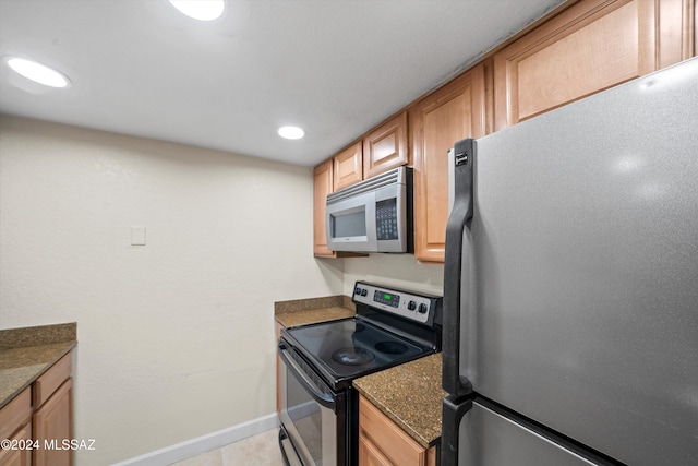 kitchen featuring dark stone countertops, light tile patterned floors, baseboards, appliances with stainless steel finishes, and recessed lighting