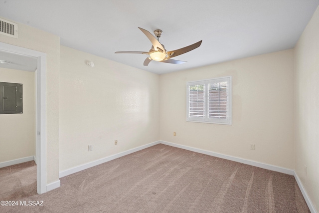 empty room with baseboards, electric panel, carpet flooring, visible vents, and ceiling fan