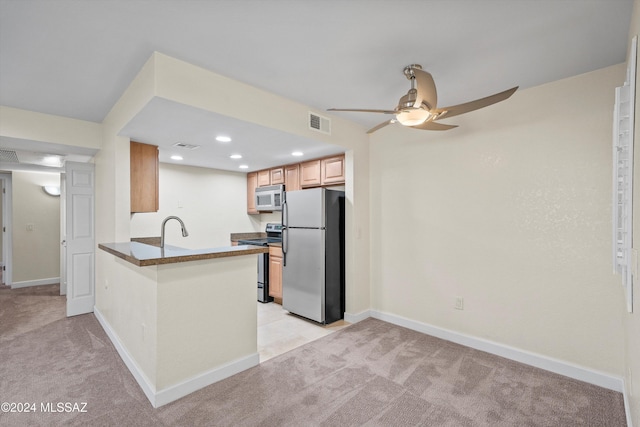 kitchen featuring light carpet, dark countertops, a ceiling fan, and stainless steel appliances
