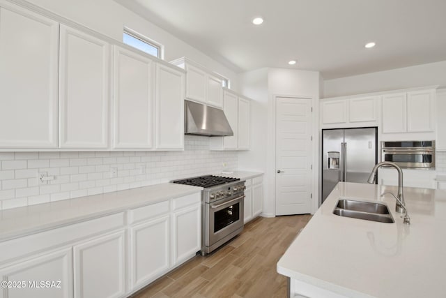 kitchen featuring under cabinet range hood, white cabinetry, a sink, and appliances with stainless steel finishes