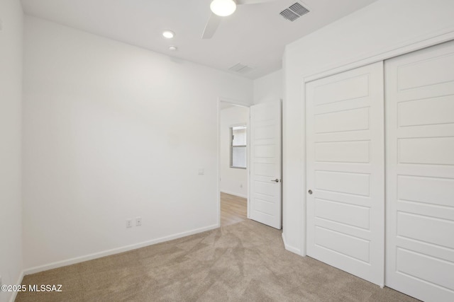unfurnished bedroom with visible vents, baseboards, a closet, a ceiling fan, and light carpet