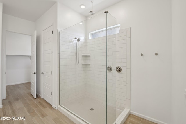 bathroom featuring a shower stall, wood finished floors, and baseboards