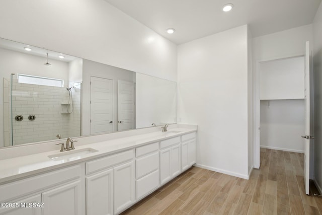full bathroom with a closet, a sink, recessed lighting, a tile shower, and wood finished floors