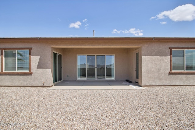 back of property with a patio and stucco siding