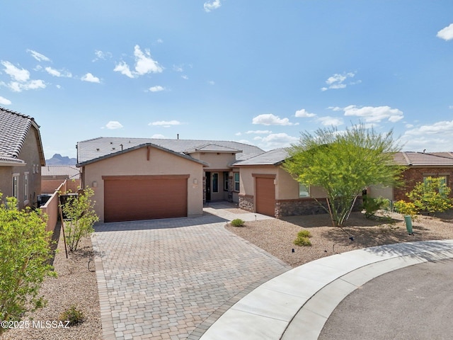 ranch-style house featuring a tile roof, decorative driveway, a garage, and stucco siding