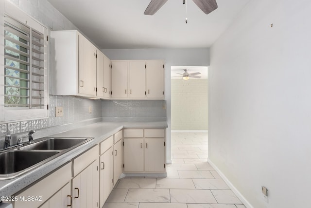 kitchen featuring tasteful backsplash, a sink, ceiling fan, light countertops, and baseboards