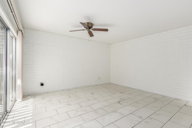 spare room featuring marble finish floor and a ceiling fan