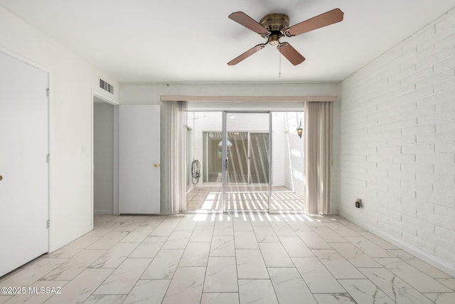 spare room featuring visible vents, marble finish floor, brick wall, and ceiling fan