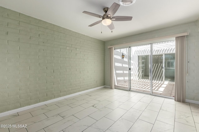spare room with brick wall, a ceiling fan, marble finish floor, and baseboards