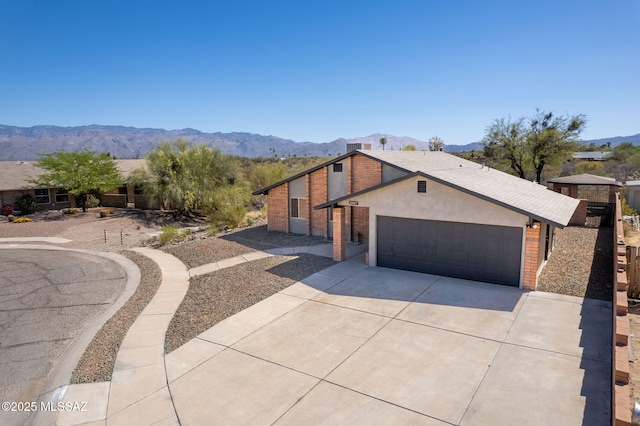 view of front of house with brick siding, a garage, a mountain view, and driveway