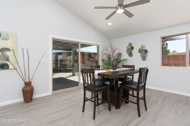 dining space featuring a ceiling fan, baseboards, lofted ceiling, and light wood-style floors
